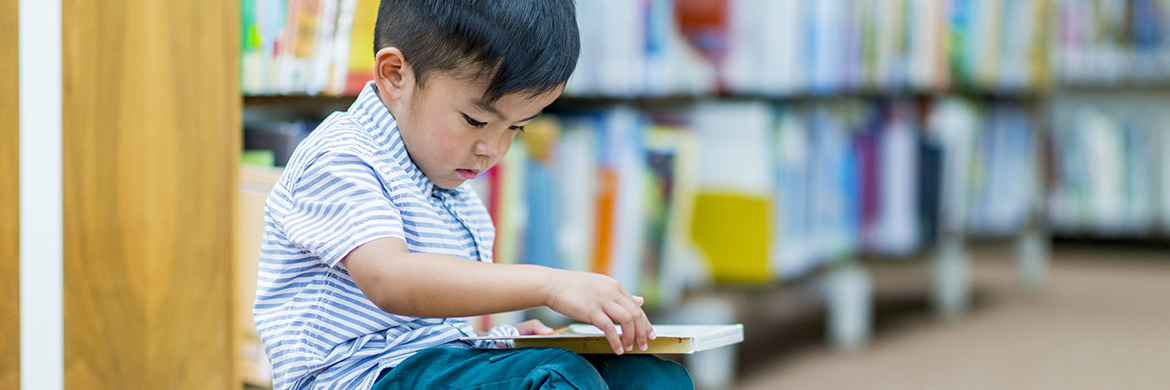 Young boy sitting in the library with an open book