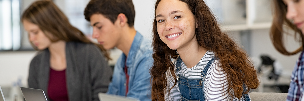 Group of tweens in a computer lab, one girl smiling at the camera